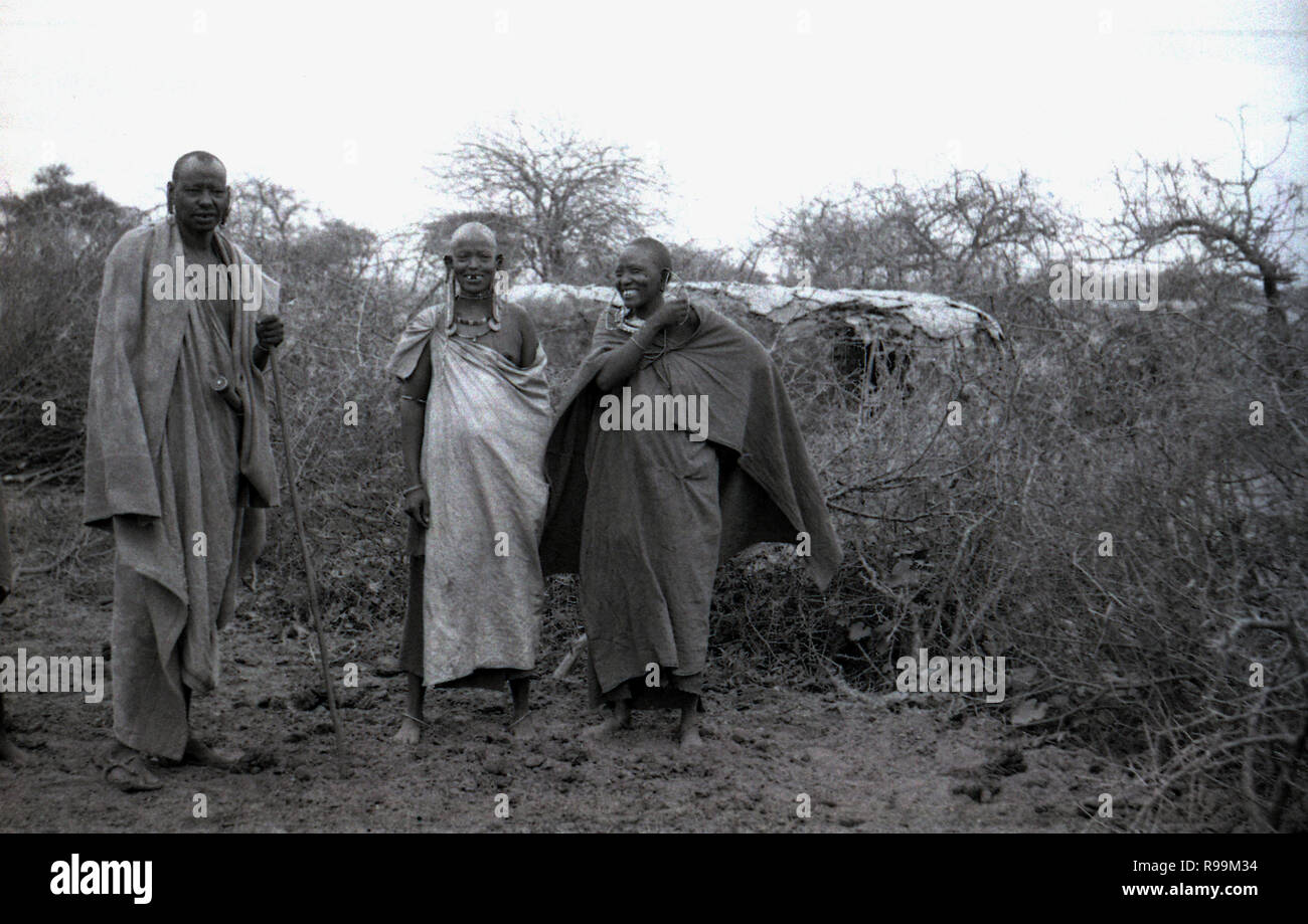 1960, historique, Maasai, dans le bush africain, homme debout avec deux femmes, toutes deux enceintes, Kenya. Les tribus Maasai sont un groupe de Nilotic de personnes vivant un style de vie semi-nomade de herder et parlent la langue Maa. Banque D'Images