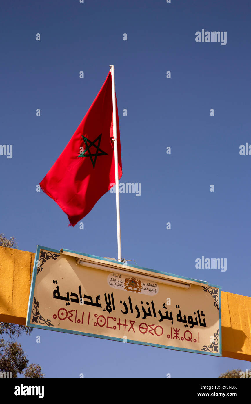 Le Maroc, Province d'Errachidia, Rissani, drapeau national au-dessus de la porte de l'école Inscription en Arabe et Berbère script Banque D'Images