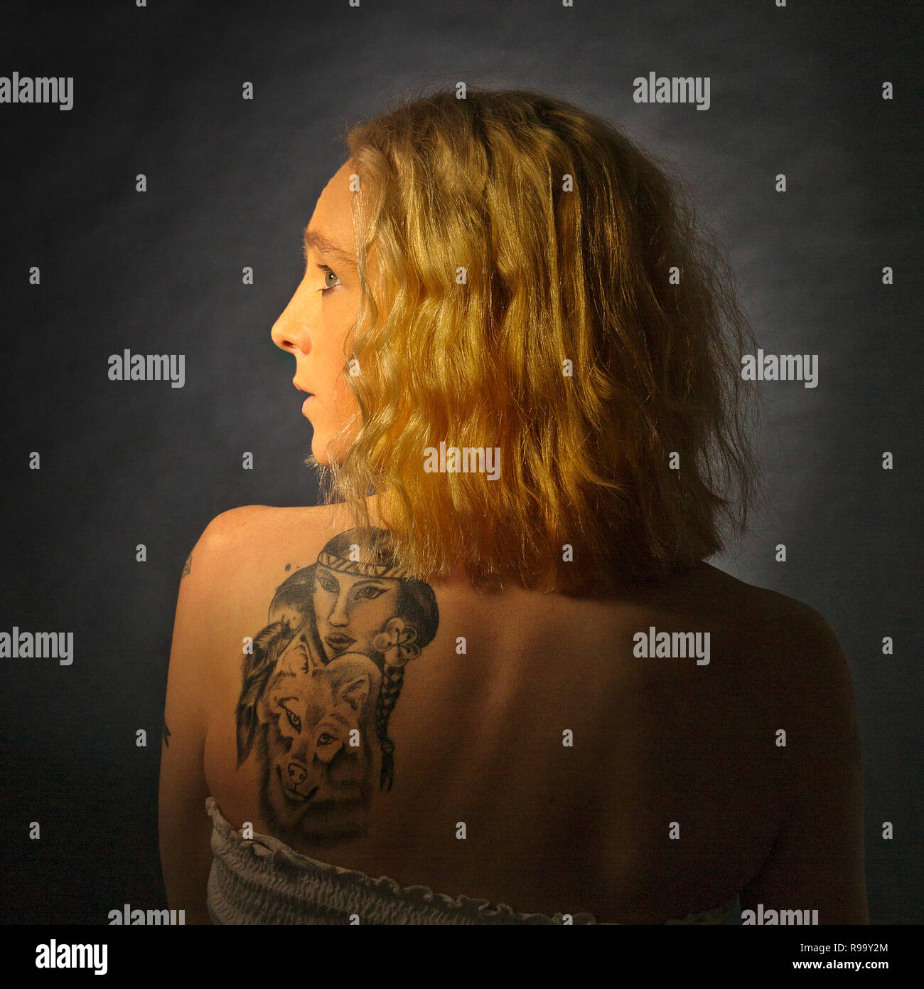 Une jeune fille blonde avec un dos tatoué Banque D'Images