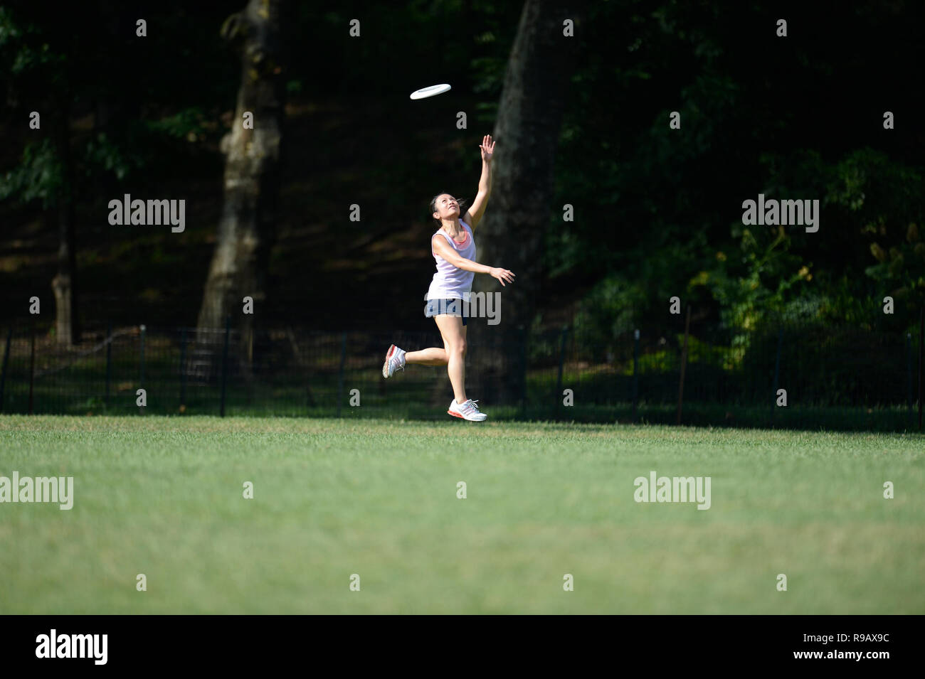Girl playing frisbee dans Central Park à New York City Banque D'Images