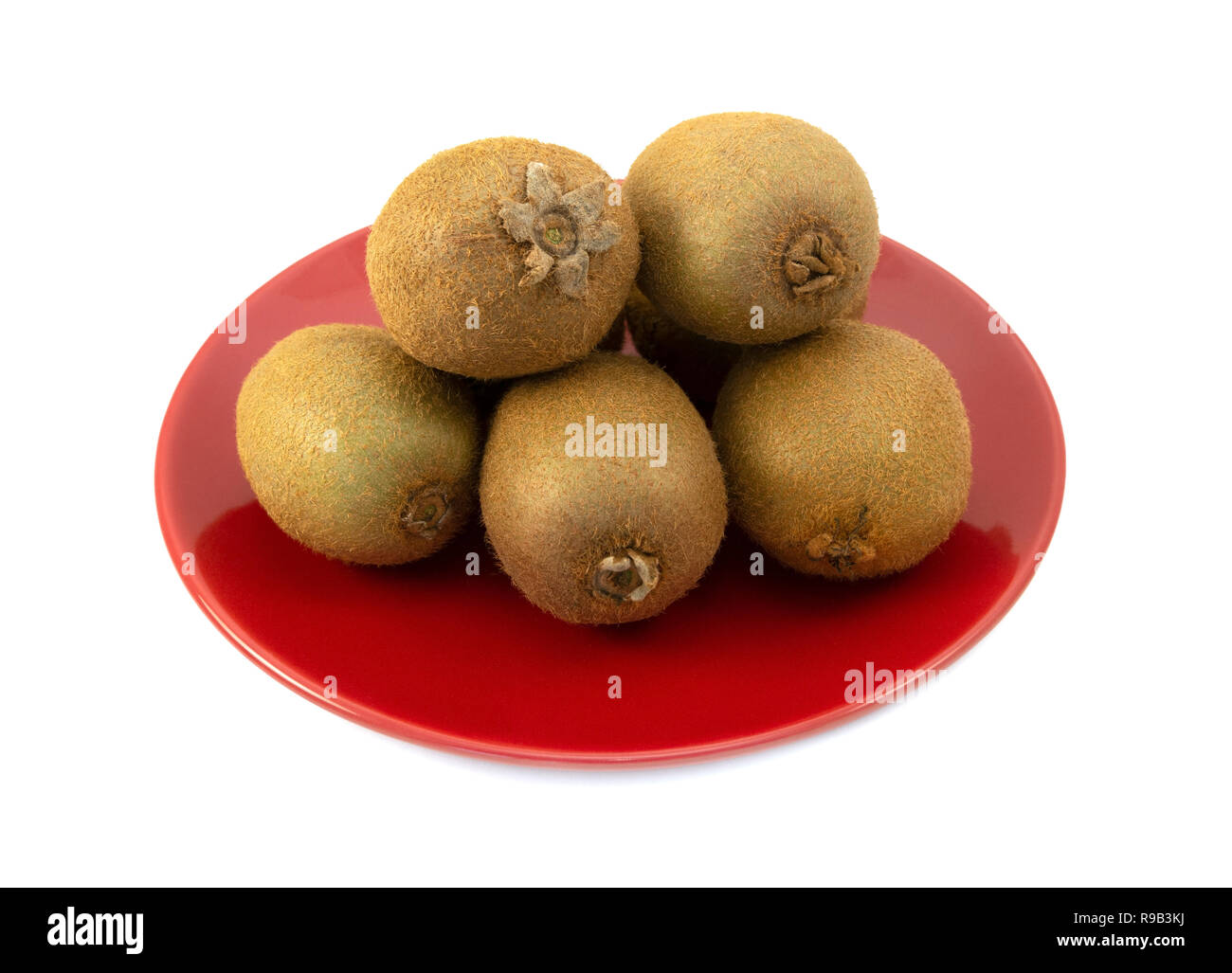 Ensemble avec kiwifruits peaux velues empilés sur une plaque rouge sur un fond blanc. Les sépales, les extrémités de la tige et des fleurs se termine du fruit sont visibles. Banque D'Images