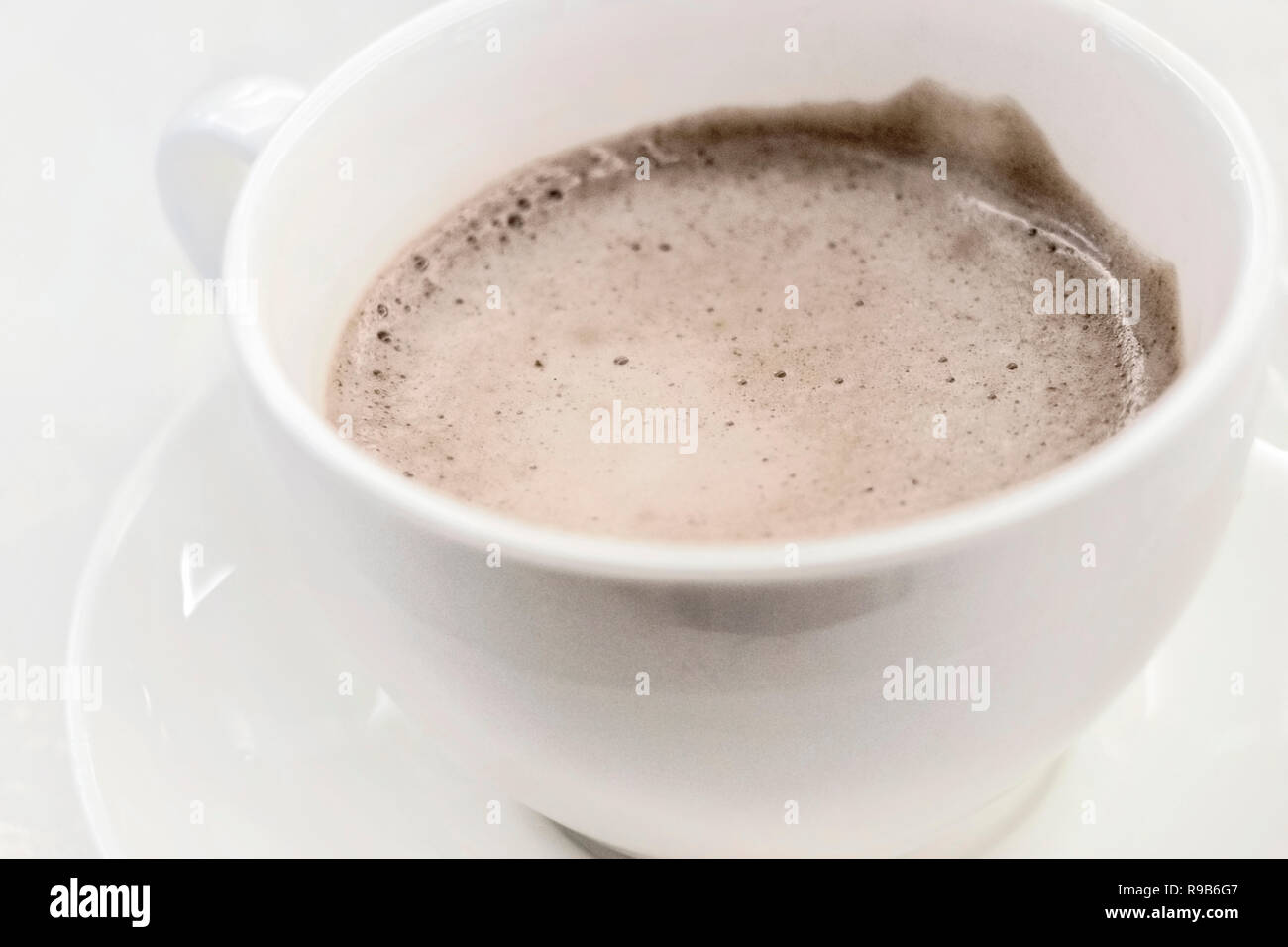 Tasse blanche avec du cacao du matin avec une mousse blanche est sur soucoupe close-up Banque D'Images