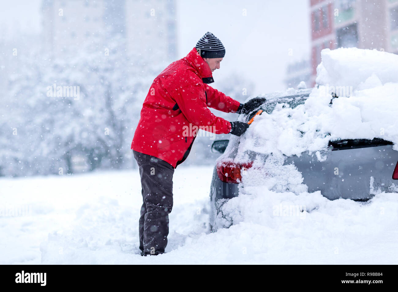 Nettoyage voiture jeune homme gelé recouvert de neige au jour d'hiver, Banque D'Images