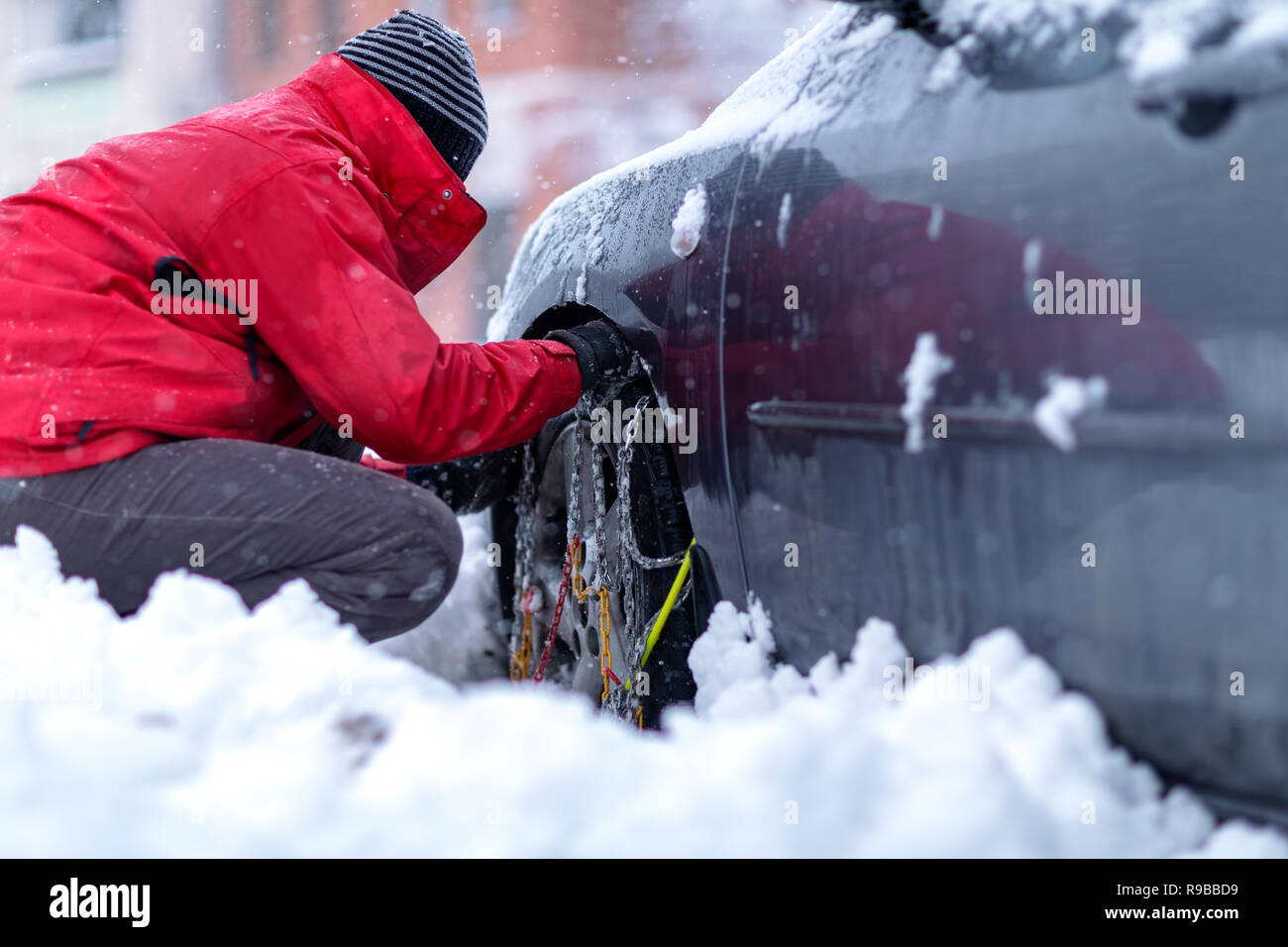 Les chaînes à neige sur les roues de voiture. Jeune homme la préparation de voiture pour se rendre à la journée d'hiver. Banque D'Images