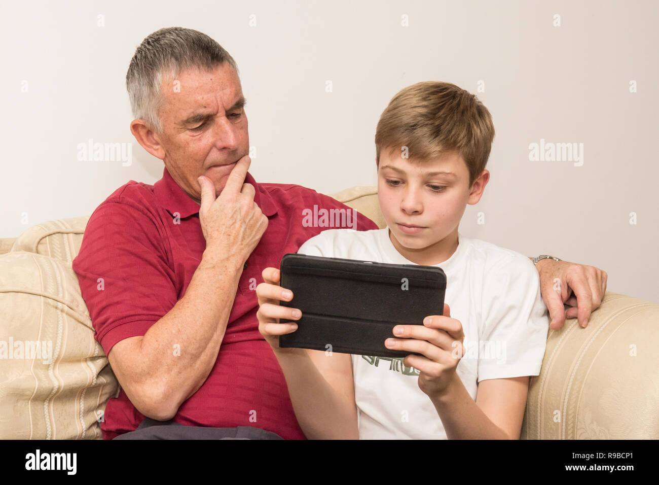 Petit-fils d'aider grand-père avec tablette, appareil électronique, les médias sociaux de la technologie moderne. Le vieillissement aidant garçon père avec l'iPad, tablette. Banque D'Images