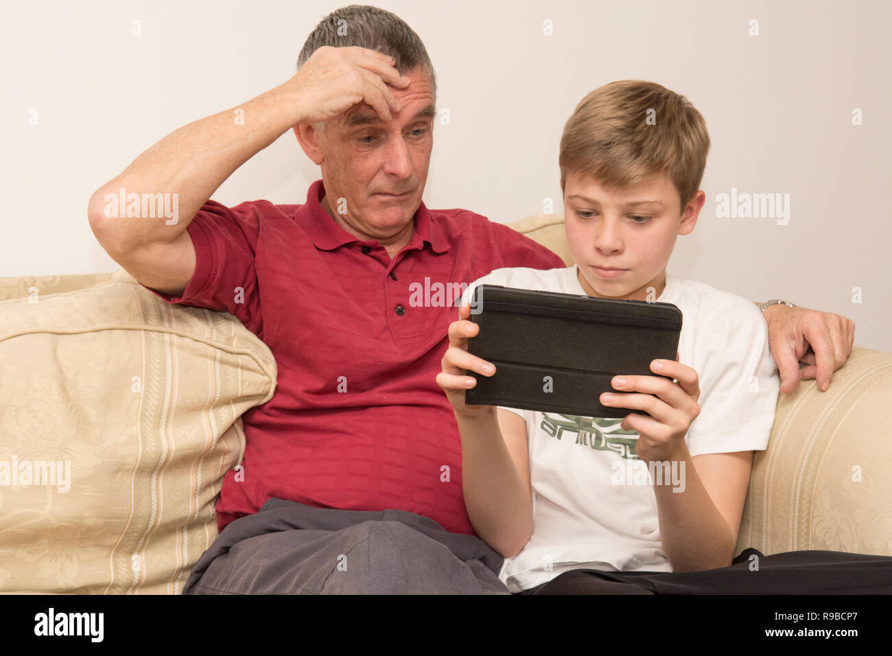 Petit-fils d'aider grand-père avec tablette, appareil électronique, les médias sociaux de la technologie moderne. Le vieillissement aidant garçon père avec l'iPad, tablette. Banque D'Images