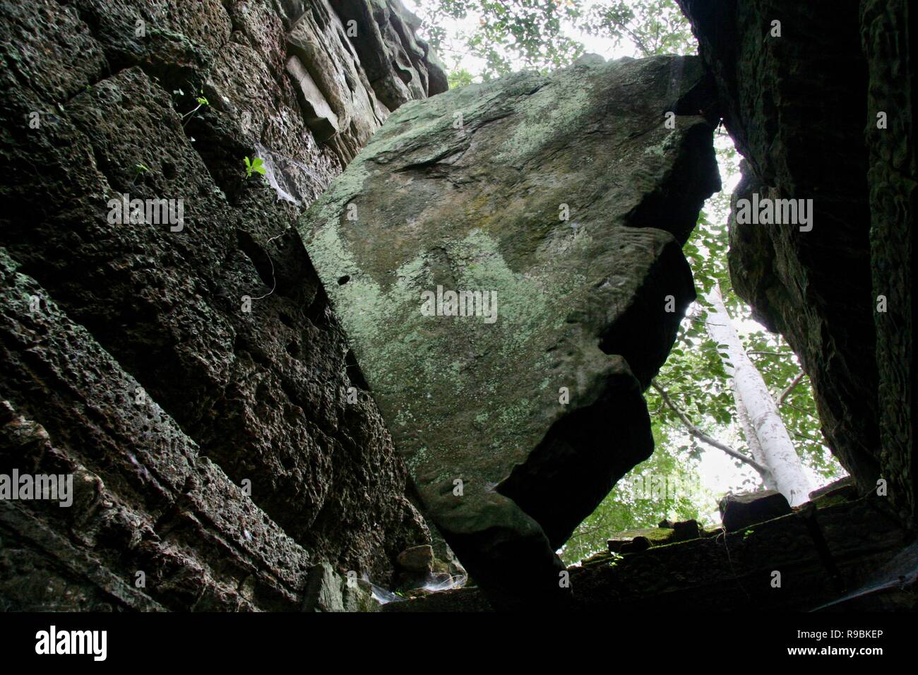 Un énorme rocher pris et coincé entre deux murs de pierre Banque D'Images