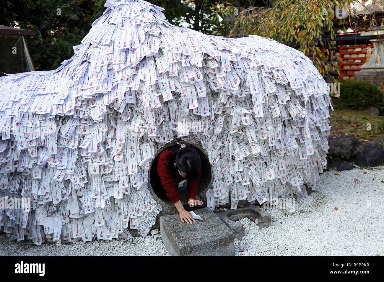 Fille de ramper à travers tunnel de dire de fortune papier glisse, Gion, Kyoto, Japon Banque D'Images