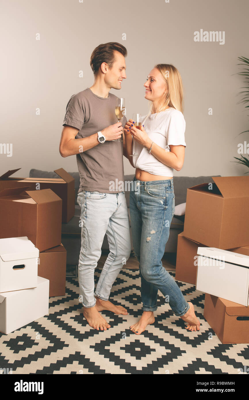 Image de l'heureux couple avec des verres à vin parmi les commandes de boîtes de carton Banque D'Images