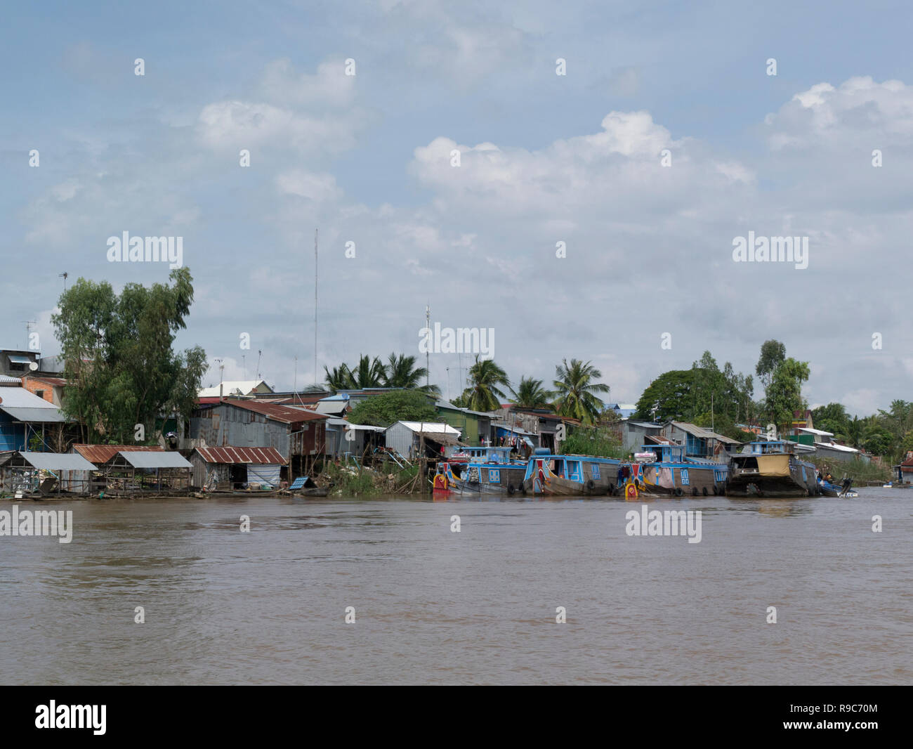 Village cambodgien sur côté du Mékong vu de ferry sur l'excursion de Chau Doc à Phnom Penh Cambodge Vietnam Asie sampans et rive en bois Banque D'Images