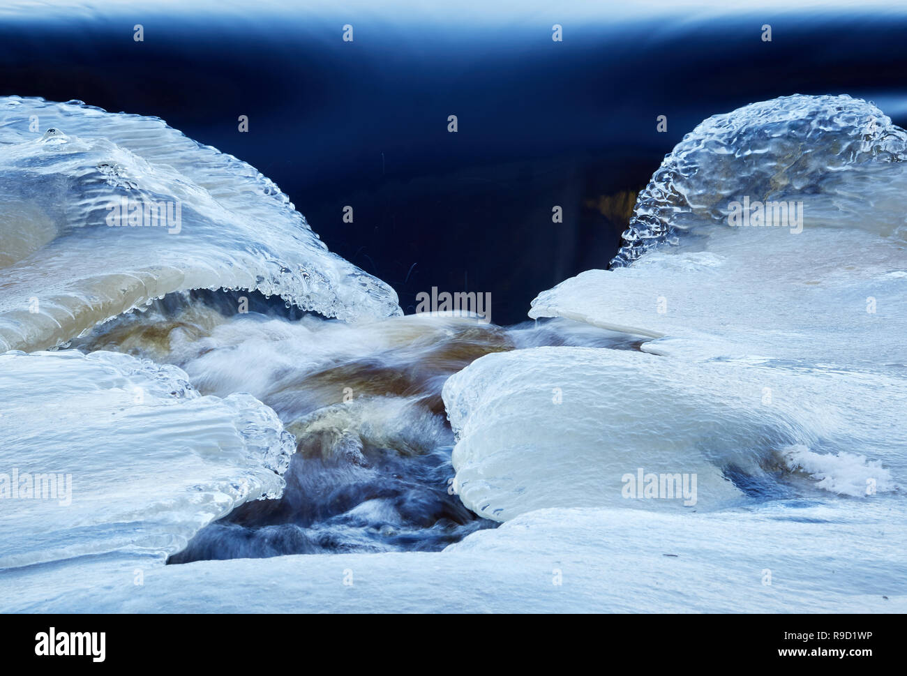 Rivière gelée enrobé de glace avec le givre et la neige avec la diffusion d'eau en hiver. Banque D'Images Rivière gelée enrobé de glace avec le givre et la neige avec la diffusion d'eau en hiver. Banque D'Images