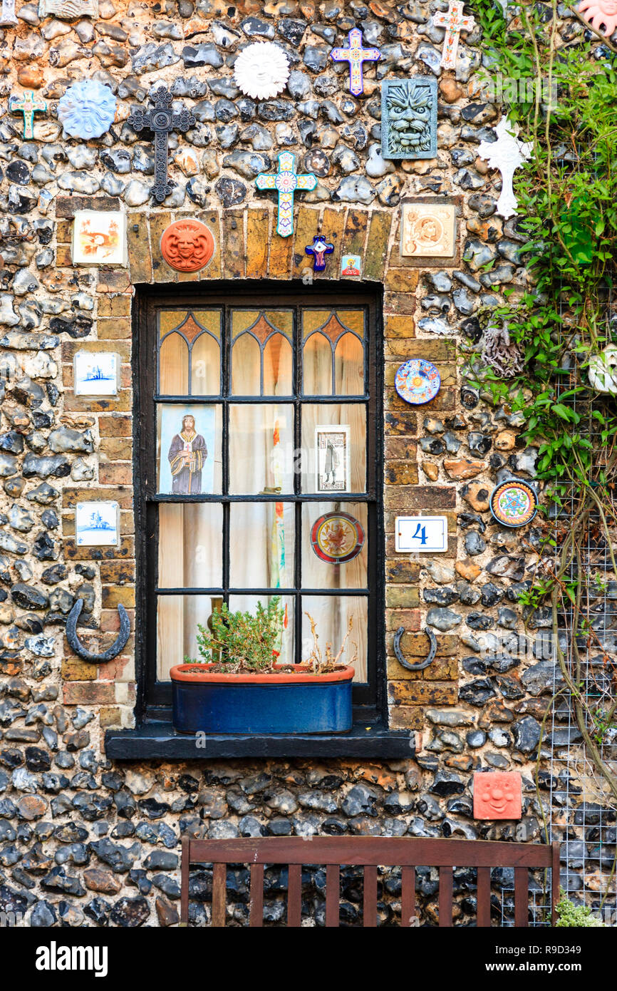 De petites fenêtres avec pierre et terrasse en brique maison décorée sur l'avant avec différentes icônes religieuses chrétiennes et insignes. Place de l'église, Broadstairs. Banque D'Images
