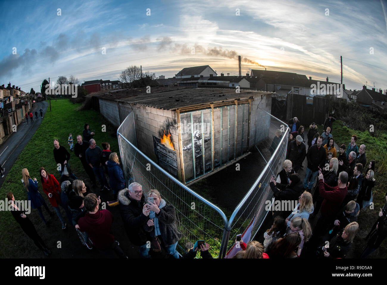 Les gens se rassemblent autour de clôtures érigés pour protéger le dernier dessin de l'artiste Banksy sur un mur de garage dans la région de Port Talbot Taibach en Galles du Sud. Banque D'Images