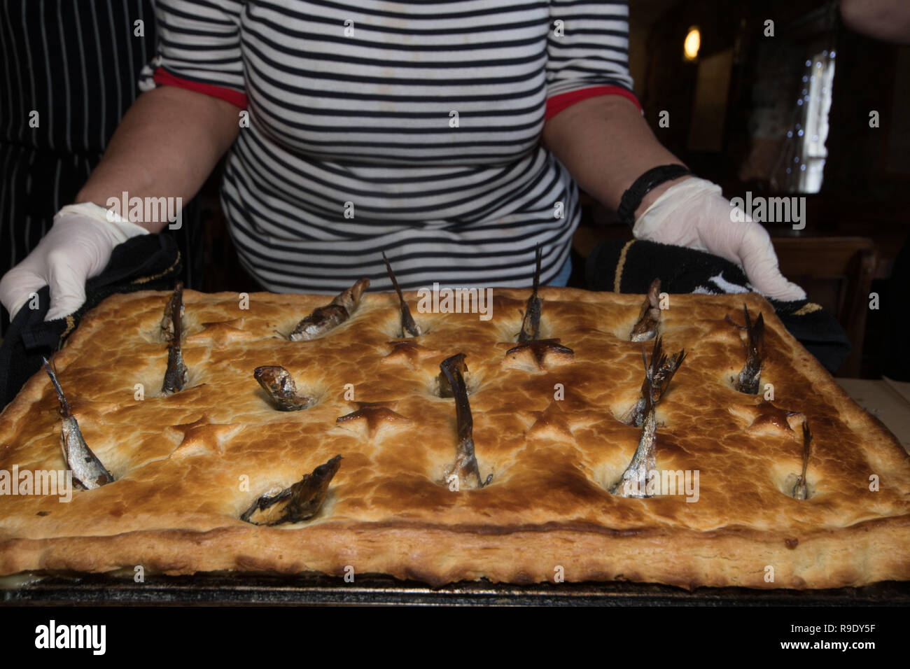 Mousehole, Cornwall, UK. Dec 23, 2018. Le personnel de l'auberge de bateau faisant ressortir la traditionnelle Stargazy pie dans l'auberge de bateau à Mousehole. La tarte poisson avec têtes et queues de Sardine poussant hors de la Chambre, est servi dans le pub sur Tom Bawcocks Eve l'histoire raconte que Tom, un pêcheur du 16ème siècle, ont bravé les tempêtes et pris assez de poissons pour nourrir tout le village. Crédit : Simon Maycock/Alamy Live News Banque D'Images