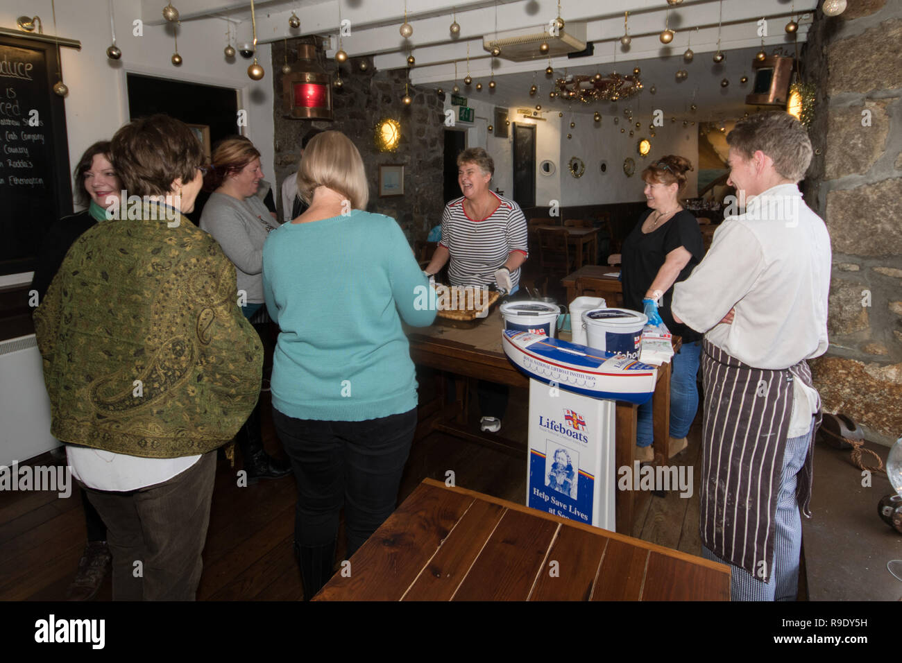 Mousehole, Cornwall, UK. 23 Nov, 2018. Mousehole, Cornwall, UK. 23 décembre 2018. Les visiteurs de l'auberge de bateau de prendre une photo de la traditionnelle tarte à la Stargazy Ship Inn à Mousehole, avec le propriétaire, le personnel du restaurant et cuisine dans l'arrière-plan. La tarte poisson avec têtes et queues de Sardine poussant hors de la Chambre, est servi dans le pub sur Tom Bawcocks Eve l'histoire raconte que Tom, un pêcheur du 16ème siècle, ont bravé les tempêtes et pris assez de poissons pour nourrir tout le village. Crédit : Simon Maycock/Alamy Live News Banque D'Images