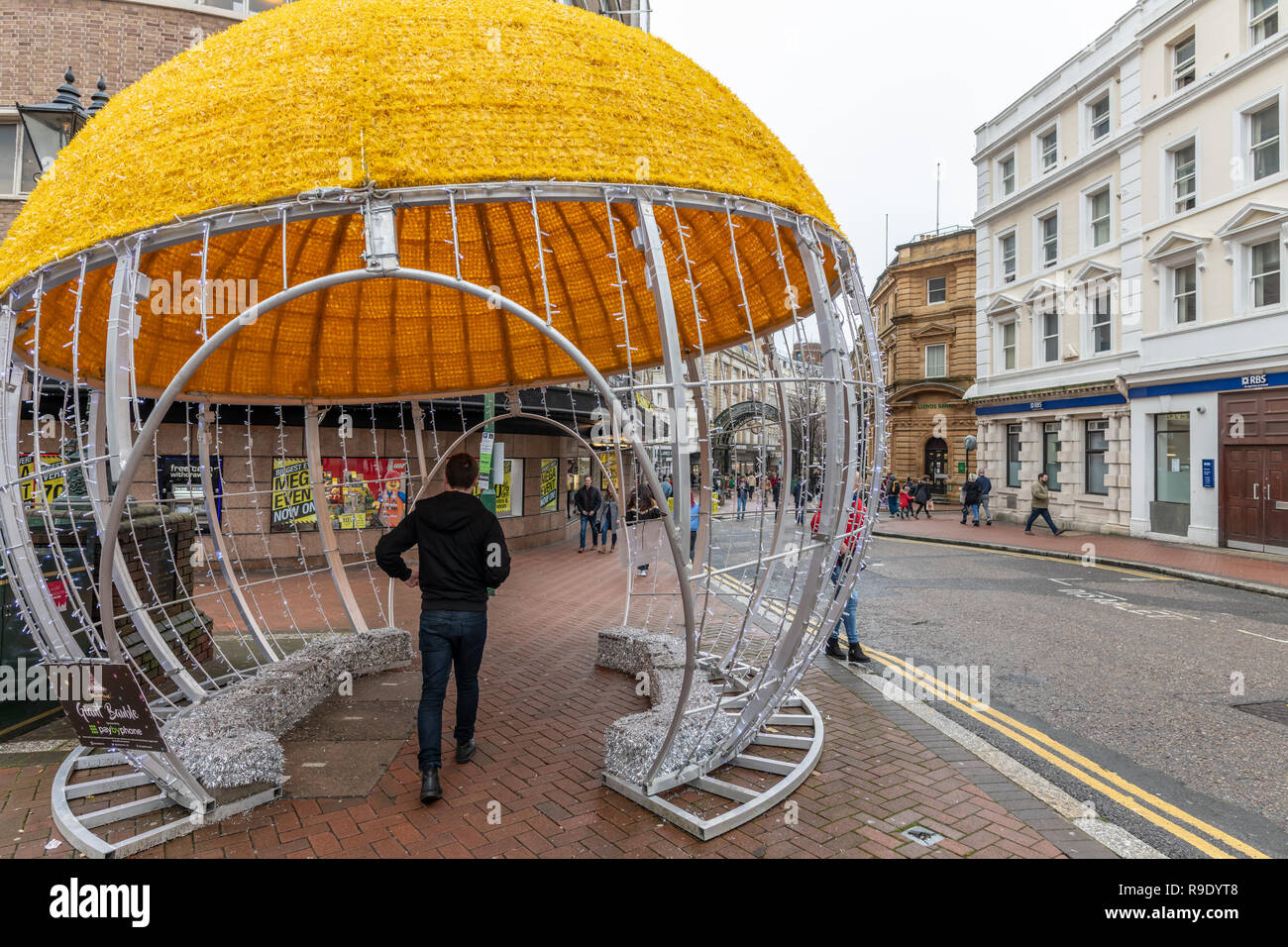 Bournemouth, Royaume-Uni. 23 décembre 2018. Un homme marche à travers un gigantesque boule de Noël sur la rue en centre-ville de Bournemouth. Crédit : Thomas Faull/Alamy Live News Banque D'Images