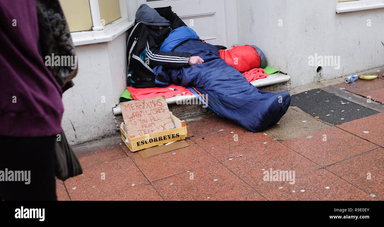 Brighton, UK. 23 décembre 2018. Un sans-abri avec un message de fête, dort dans une porte à Brighton comme acheteurs de Noël étaient en vigueur Crédit : Simon Dack/Alamy Live News Banque D'Images