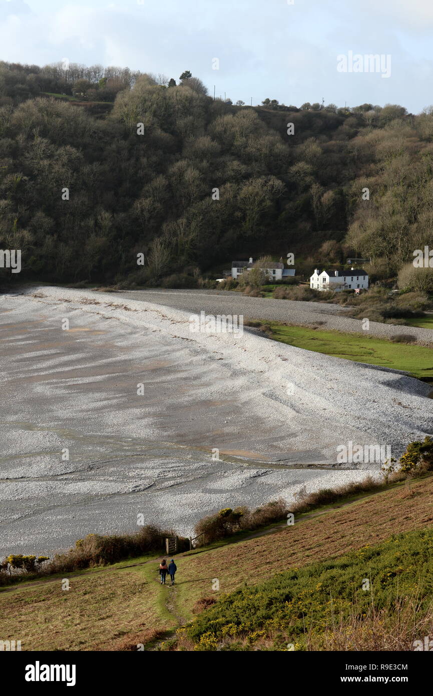 Pwlldu Bay- une petite plage de galets sur la côte sud de la péninsule de Gower, dans le sud du Pays de Galles avec 2 personnes en premier plan Banque D'Images