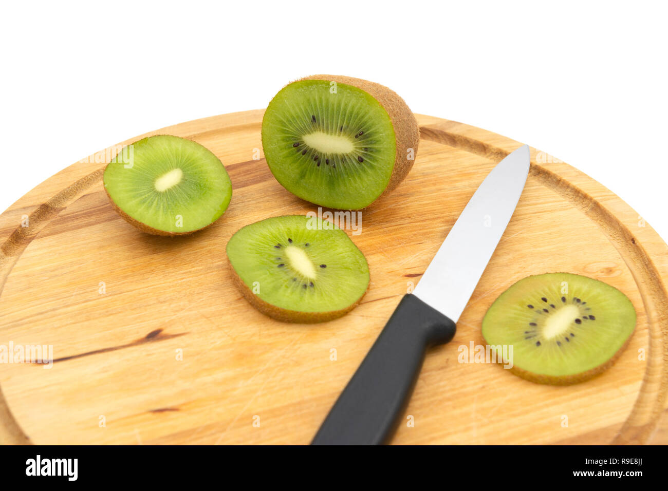 Le kiwi vert frais avec un couteau de cuisine et couper les tranches de fruits sur une planche à découper en bois. Les graines noires et chair verte afficher dans la section efficace. Banque D'Images