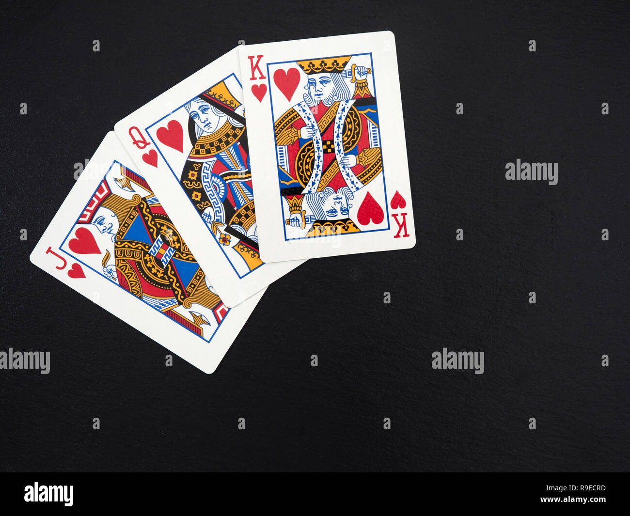 Poker, jeu de cartes français, chiffres : Jack, reine, roi de cœur, sur une surface en ardoise noire Banque D'Images