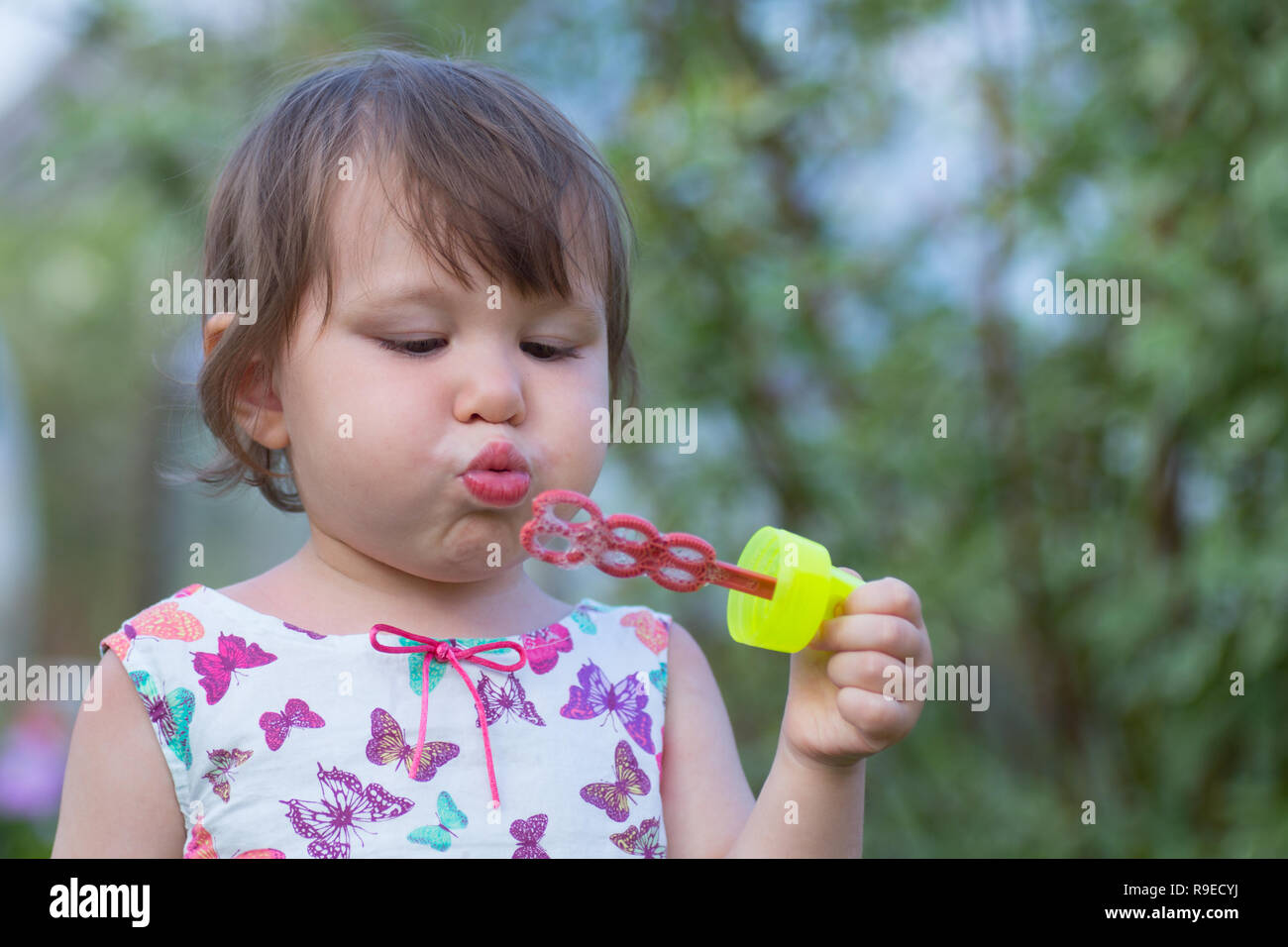 Cute little girl est un souffle des bulles de savon Banque D'Images