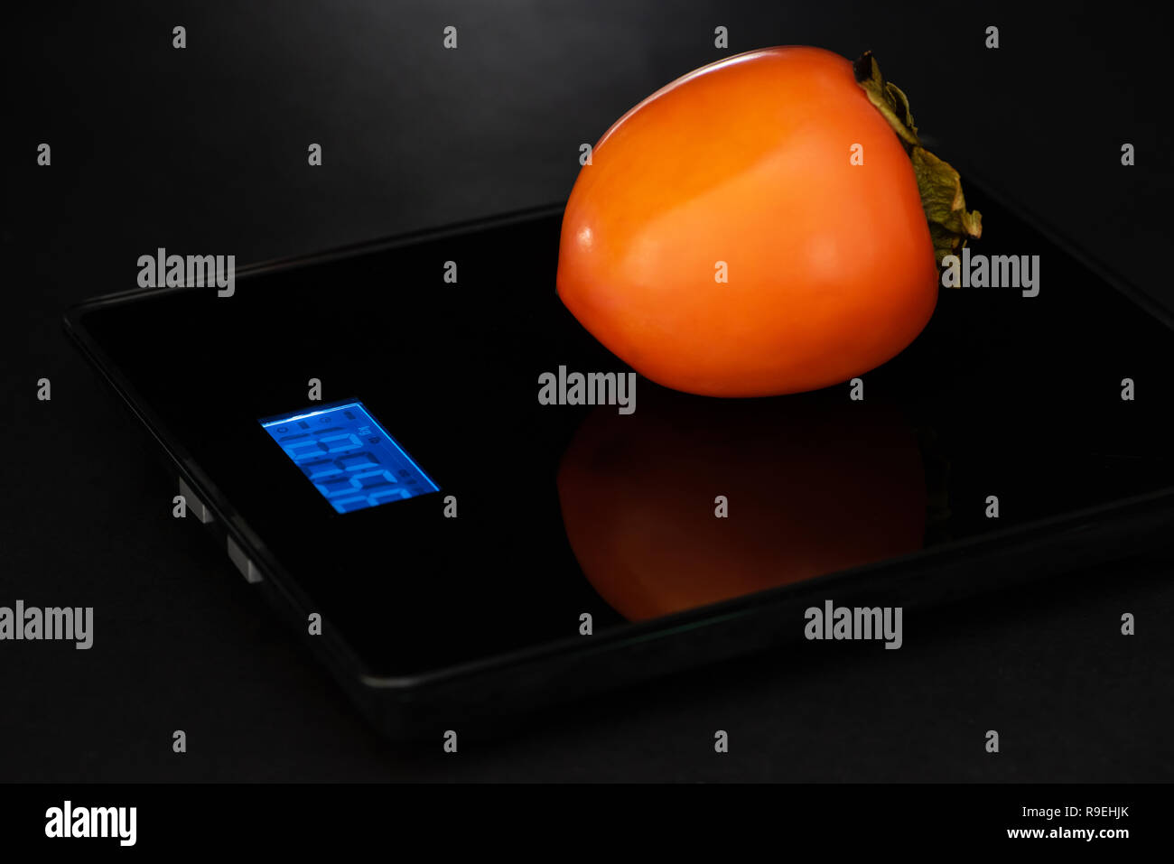 Le persimmon est sur un système électronique de masse sur un fond noir. Banque D'Images