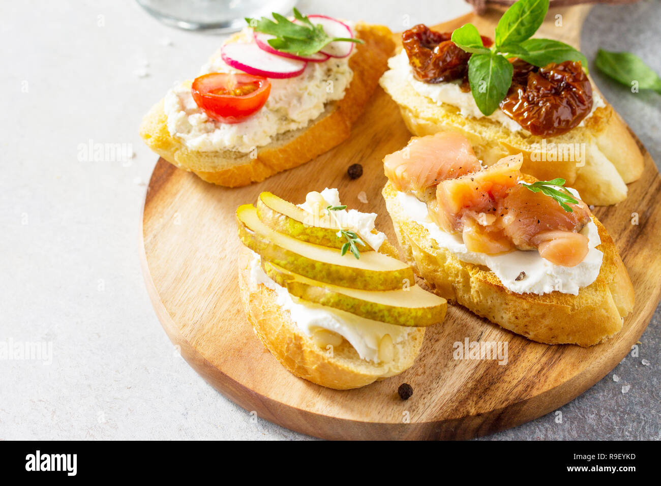 Antipasti italiens collations set close-up pour le vin. Brushetta avec fromage, poire, radis, le saumon et les tomates séchées sur un fond noir en lumière. Banque D'Images