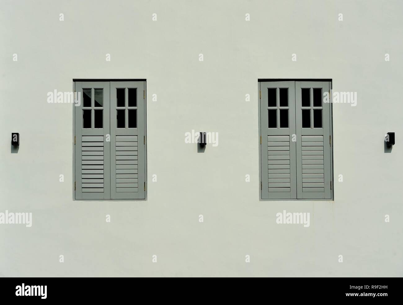 Vue avant du vintage boutique traditionnelle Singapour extérieur de maison avec des volets en bois gris isolé sur un mur gris pâle Banque D'Images