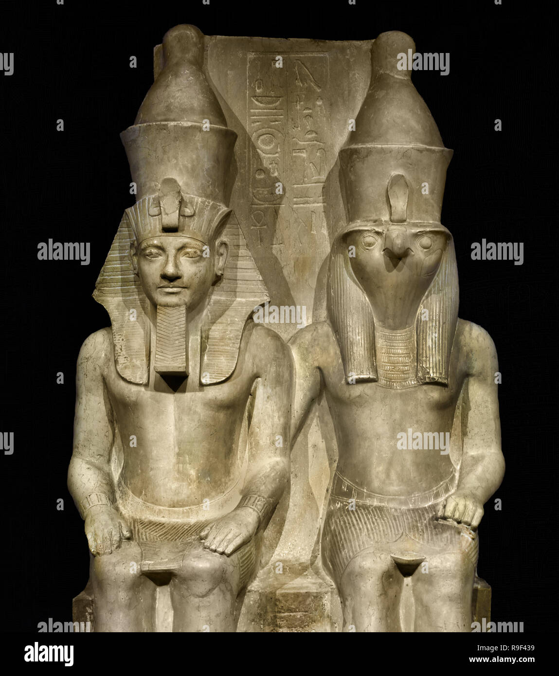 Droit d'Horus et d'Horemheb ce temple image représente le dieu Horus et le pharaon égyptien Horemheb (1319-1305 BC) assis côte à côte. Horus porte une tête de comme une puissance céleste. Le roi est de la même taille que le dieu, car selon les Égyptiens il est tout aussi puissant. Il est l'apparence terrestre d'Horus et ainsi lui-même un dieu. (1,52 mètres de calcaire : Nouvel Empire, xviiie dynastie (1319-1305 avant J.-C.) L'Égypte, l'Égyptien. Banque D'Images