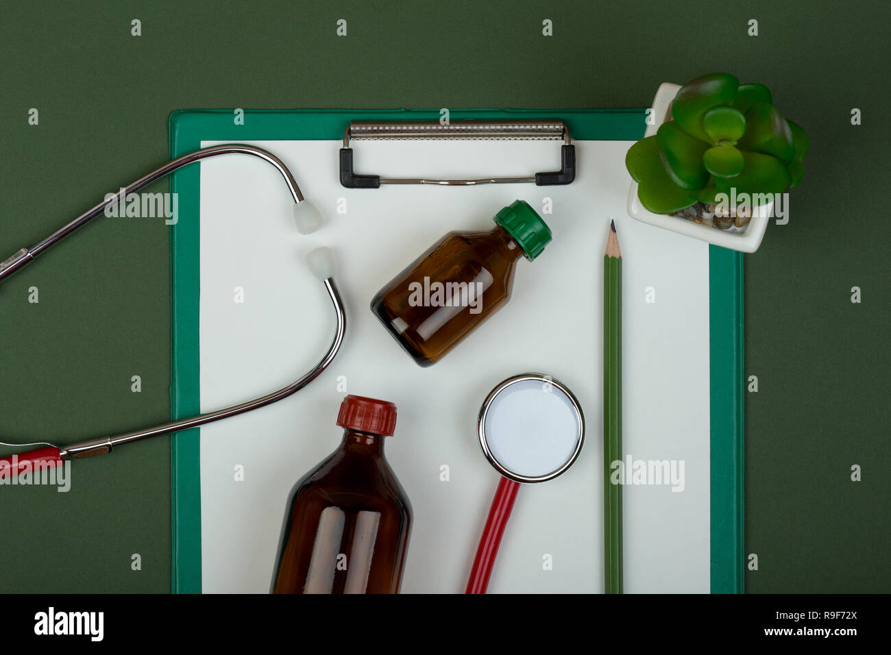 Médecin de travail - stéthoscope rouge, bouteilles et presse-papiers médicaux sur papier vert contexte Banque D'Images