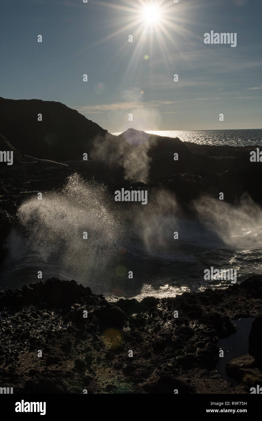 Rétro-éclairage de l'eau expulsée par un trou dans la roche lorsque les vagues pause au jaillissement Horn Banque D'Images