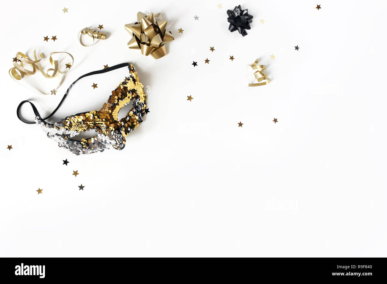 Fête de la nouvelle année de composition avec Carnival mask, noir et or confettis étoiles et des rubans. Décoration fête, célébration concept. Mise à plat, vue du dessus, Banque D'Images