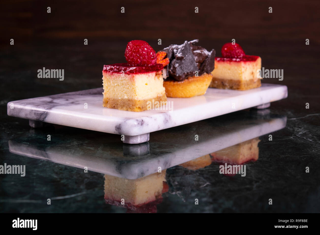 Ensemble de mini cakes en assortiment sur plaque blanche. Menu du restaurant. Gâteau aux framboises Blackberry. Avec tartelette de fruits. Close up. Banque D'Images