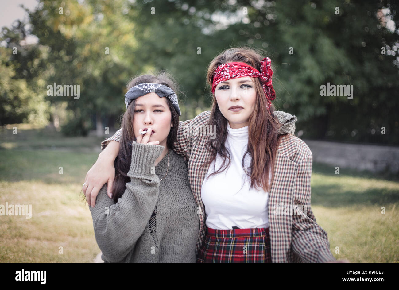 Deux filles habillées de façon informelle dans la rue avec des cigarettes. Problèmes d'adolescent. Banque D'Images