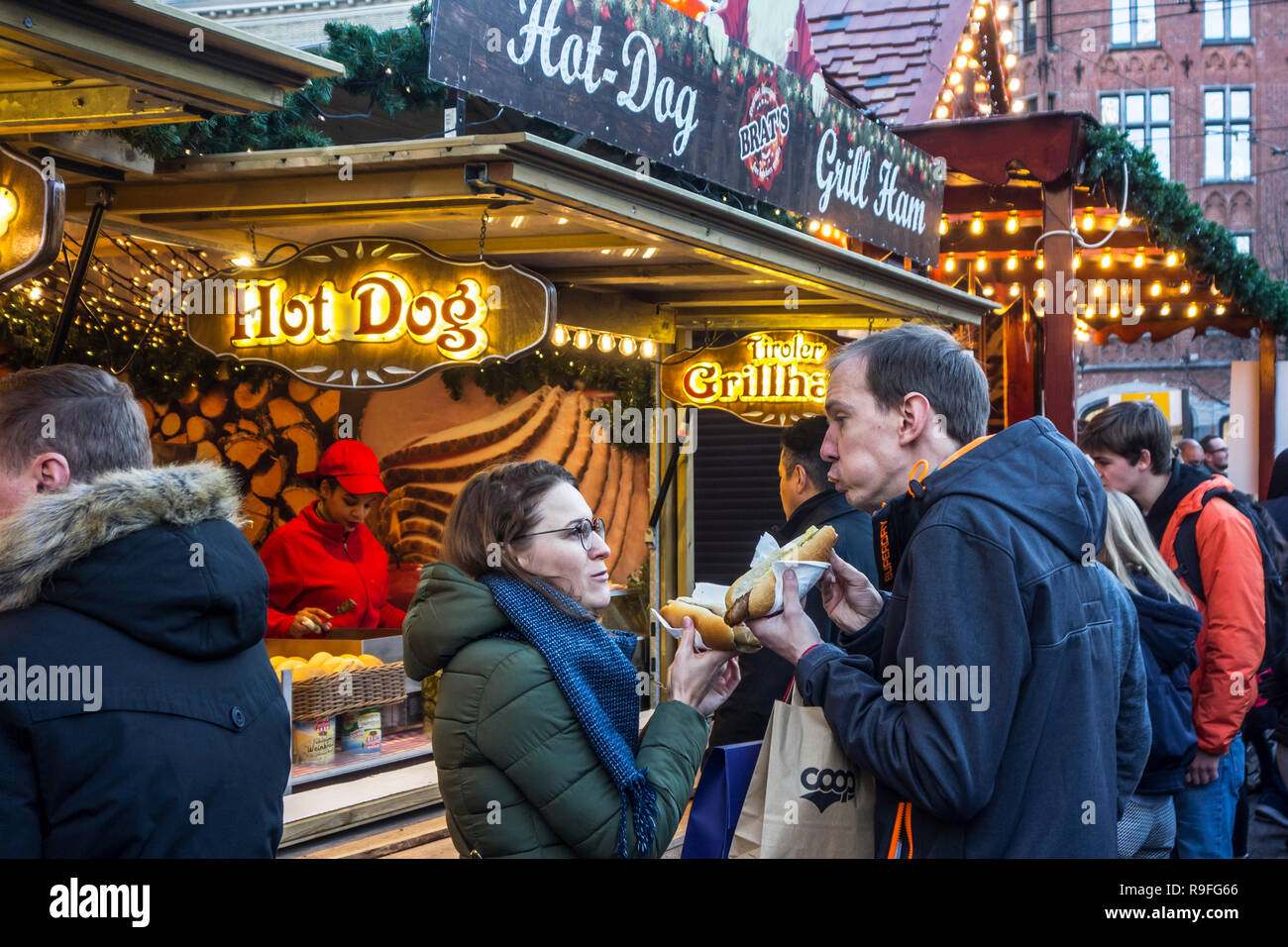 Les visiteurs du stand fast-food eating hot dogs au marché de Noël pendant les fêtes de Noël en hiver Banque D'Images