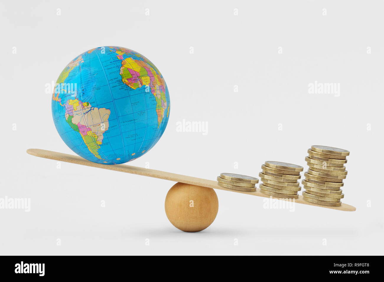 Globe terrestre et de l'échelle d'équilibre de la pile de pièces - Concept de la croissance économique la priorité sur la santé planétaire Banque D'Images