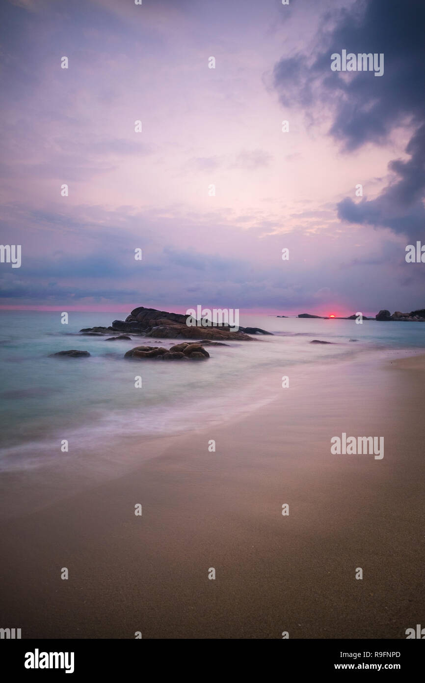 Lever du soleil sur l'île de Bintan. Sable mer ciel nuages et pierres Banque D'Images