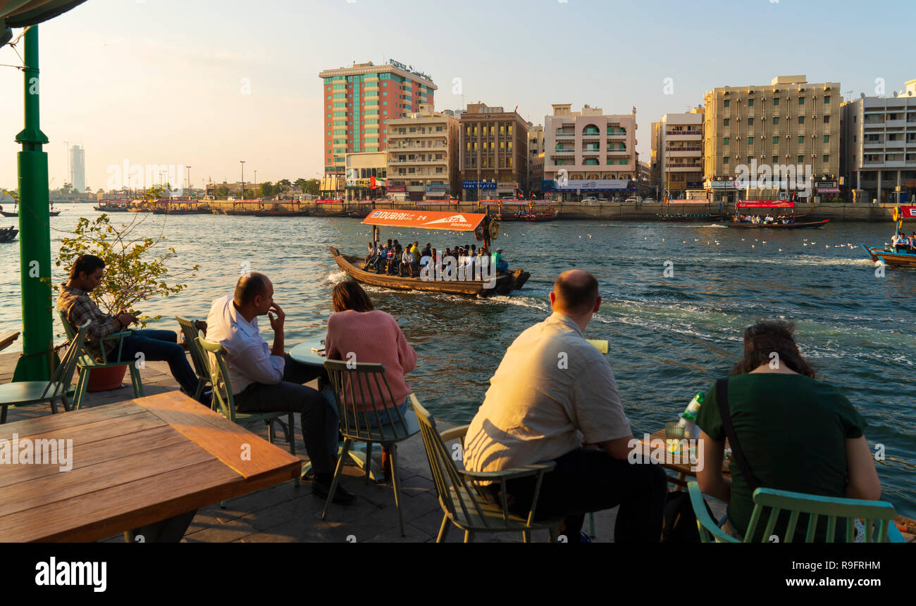 Les gens dans le café à côté du Creek au coucher du soleil dans le vieux Dubaï, Emirats Arabes Unis. Banque D'Images