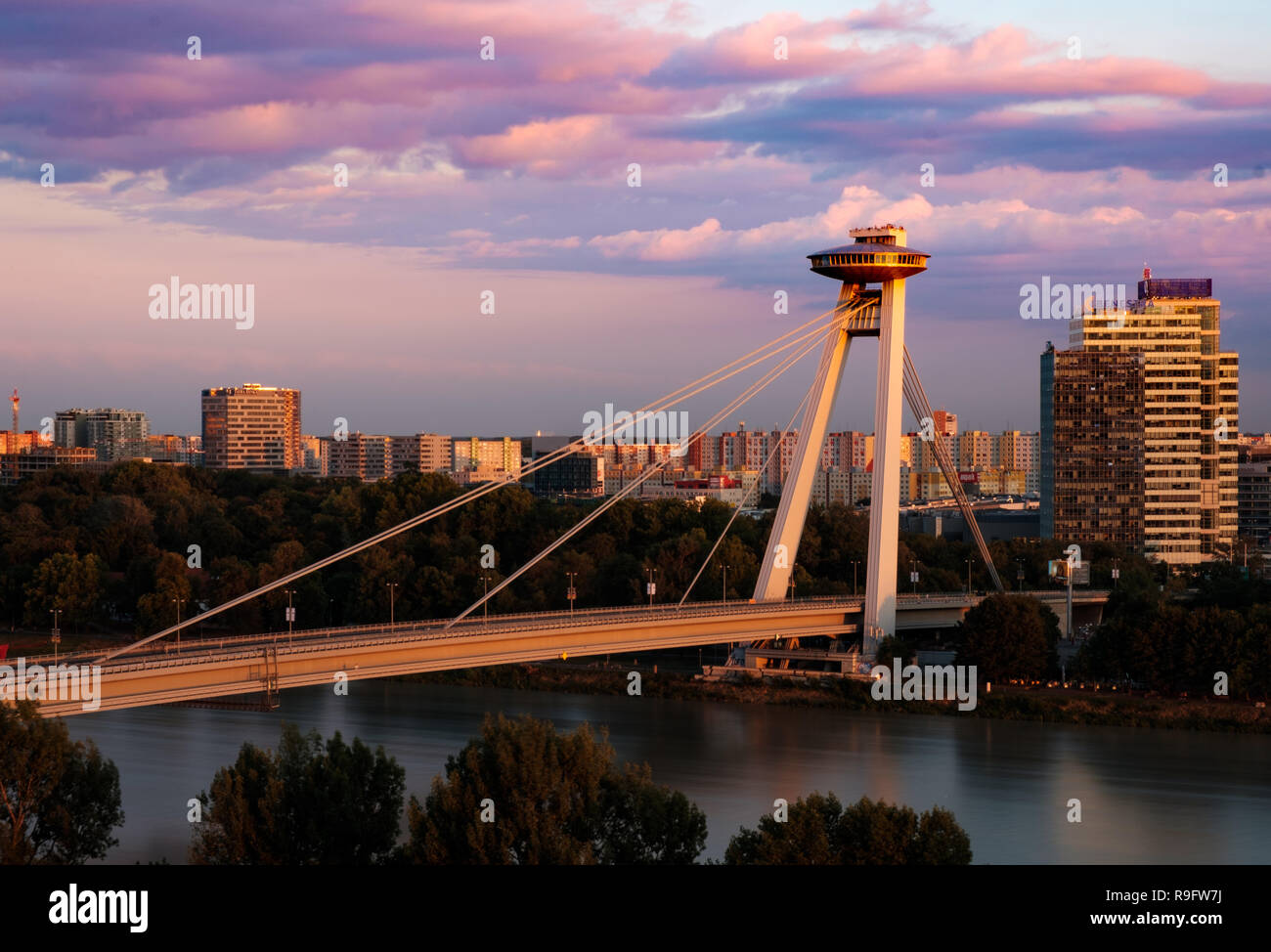 Pont (la plupart des SNP) qui relie les deux côtés de Bratislava au coucher du soleil, à la recherche comme OVNI. Bloc communiste appartements de Petrzalka en arrière-plan Banque D'Images