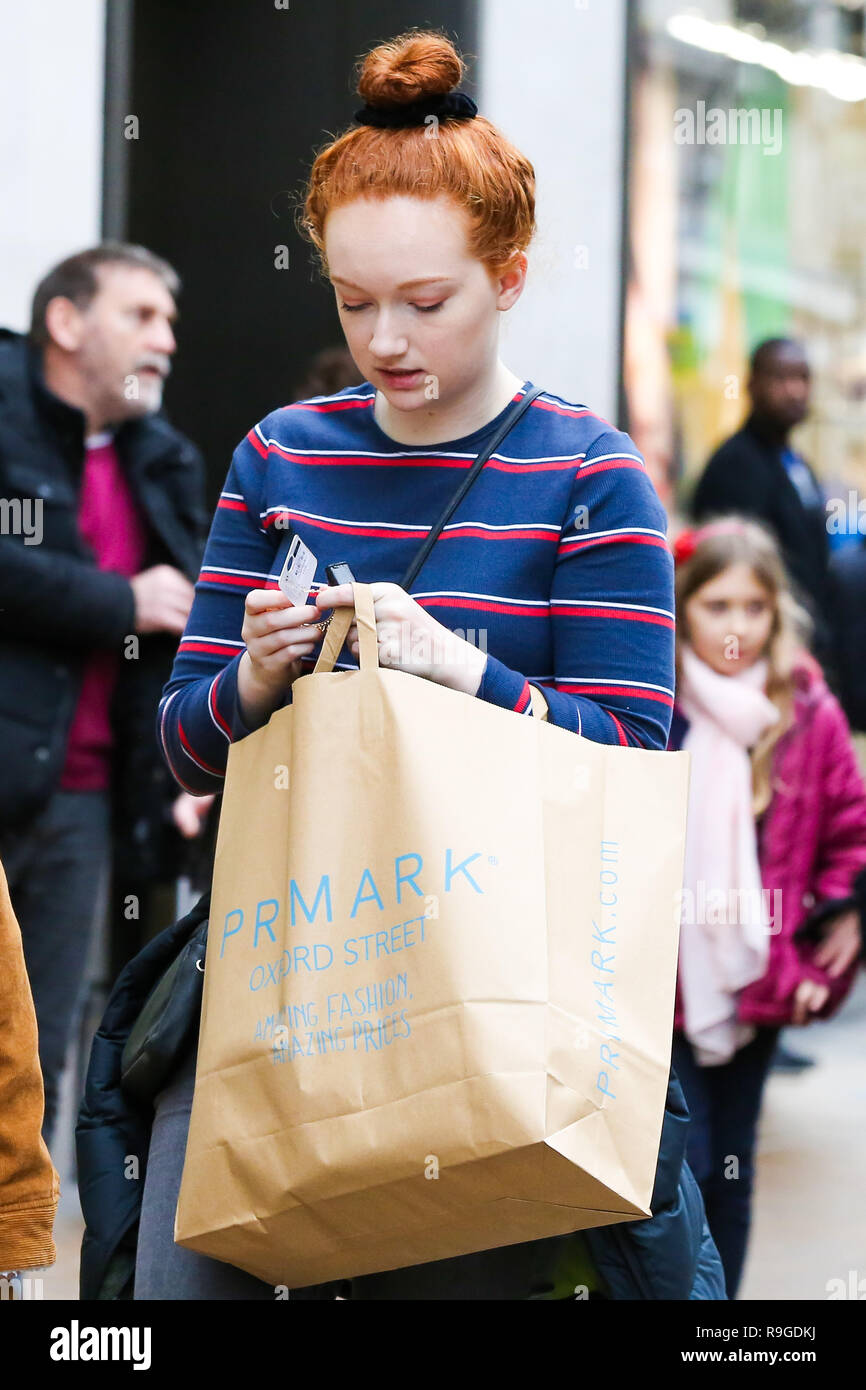Une femme est un Primark sac shopping sur Oxford Street de Londres. Les  acheteurs de Noël de dernière minute Profitez des bonnes affaires avant  Noël à Oxford Street à Londres. Moins de