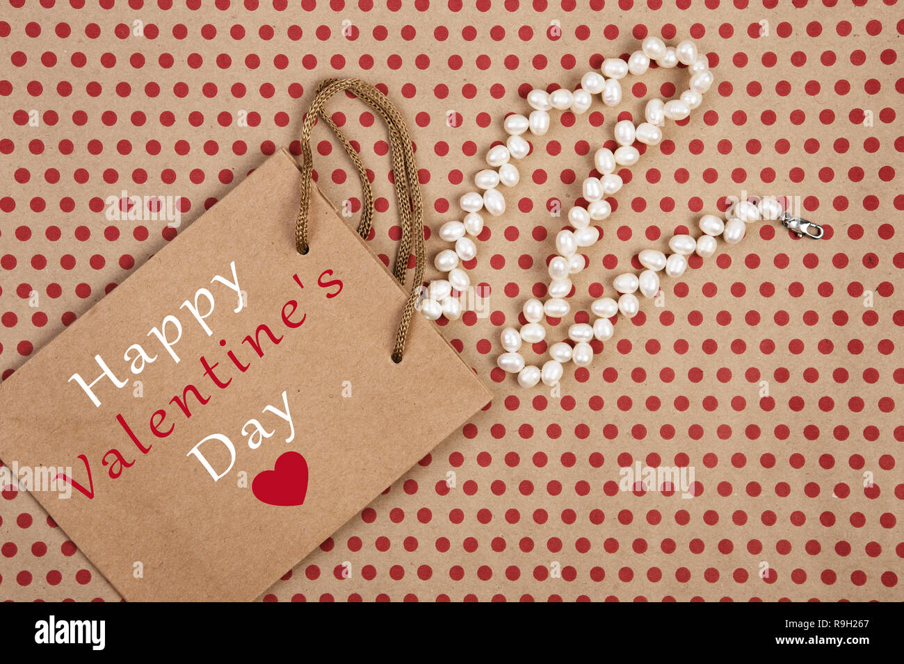 Concept de célébration - sac de shopping, sac cadeau avec texte "Happy Valentine's Day ?' et les bijoux de perles sur fond de papier de pois rouges Banque D'Images