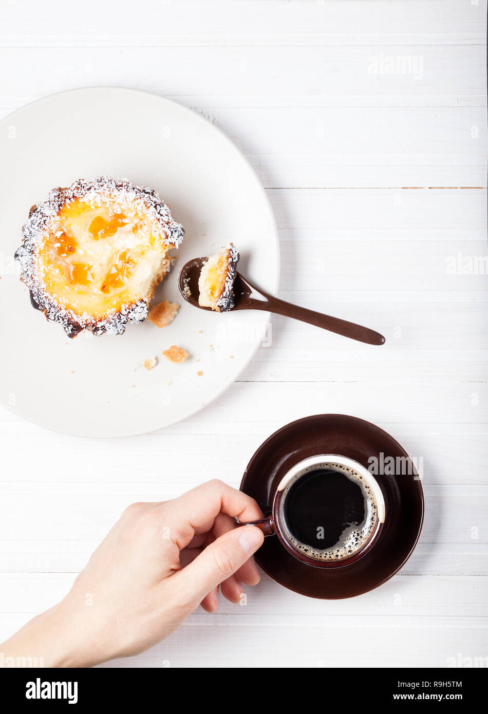 Femme de boire du café et manger un gâteau sur la table en bois blanc Banque D'Images