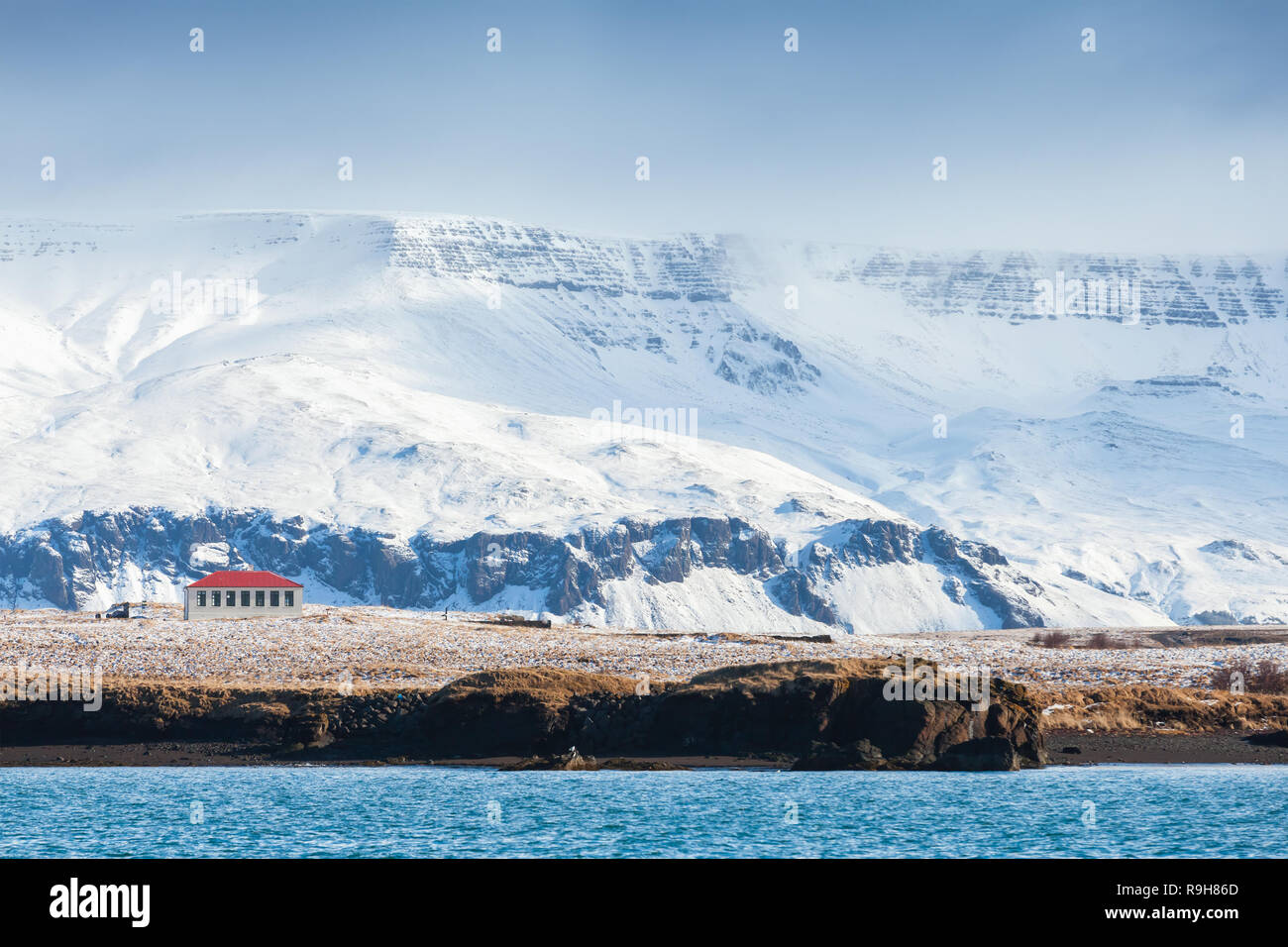 Paysage islandais côtières avec les montagnes enneigées et maison solitaire. Reykjavik, Islande Banque D'Images