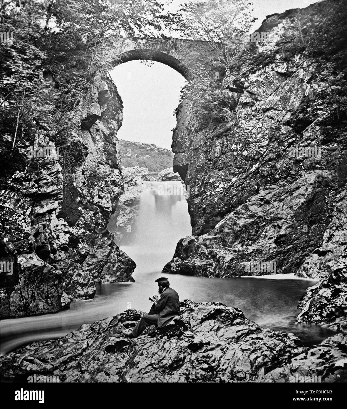 Une photographie victorienne montrant un homme assis à côté de la partie supérieure de l'automne de foyers en Ecosse.L'automne de foyers (en gaélique écossais : Smùide na EAS, ce qui signifie que les fumeurs falls) est une cascade sur la rivière Foyers, qui alimente le Loch Ness, dans les Highlands, Ecosse, Royaume-Uni. La cascade a 'une belle cascade', ayant une chute de 165 pieds. Il est situé sur la partie inférieure de la rivière. La rivière qui entre dans le Loch Ness sur le côté est, au nord-est de Fort Augustus. Banque D'Images