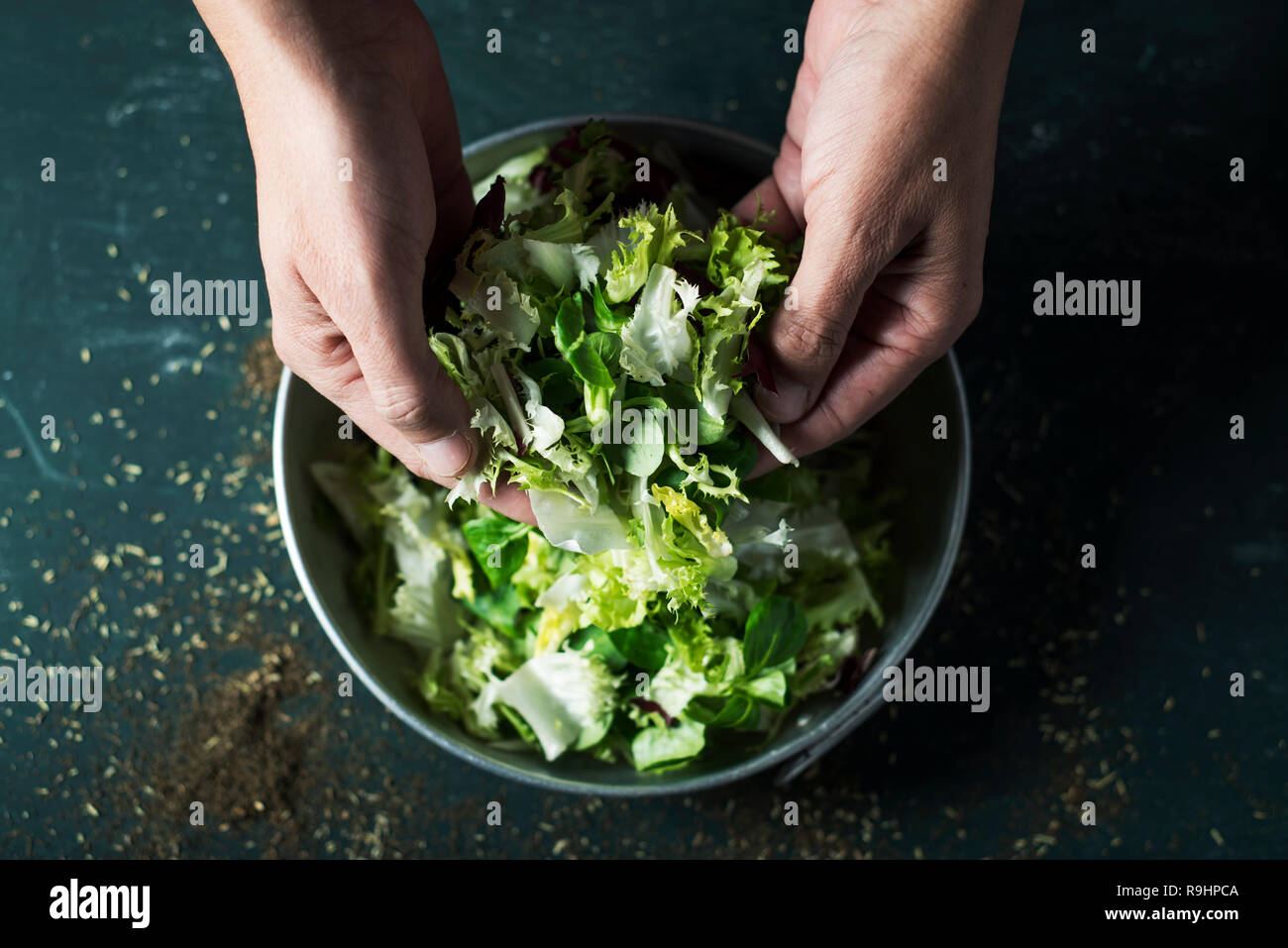 Libre d'un jeune couple sur le point de préparer une salade avec un mélange de différentes salades, comme la laitue romaine, l'endive ou de roquette, dans un cadre rustique m Banque D'Images