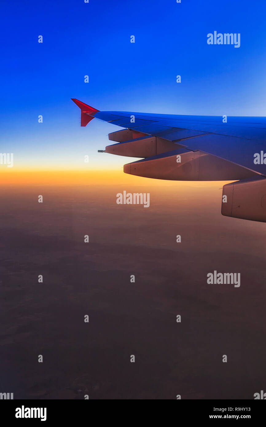 L'Est et l'horizon lointain au lever du soleil vu de haut dans le ciel à bord d'un avion en vol et fragment d'aile avec les moteurs à réaction. Banque D'Images
