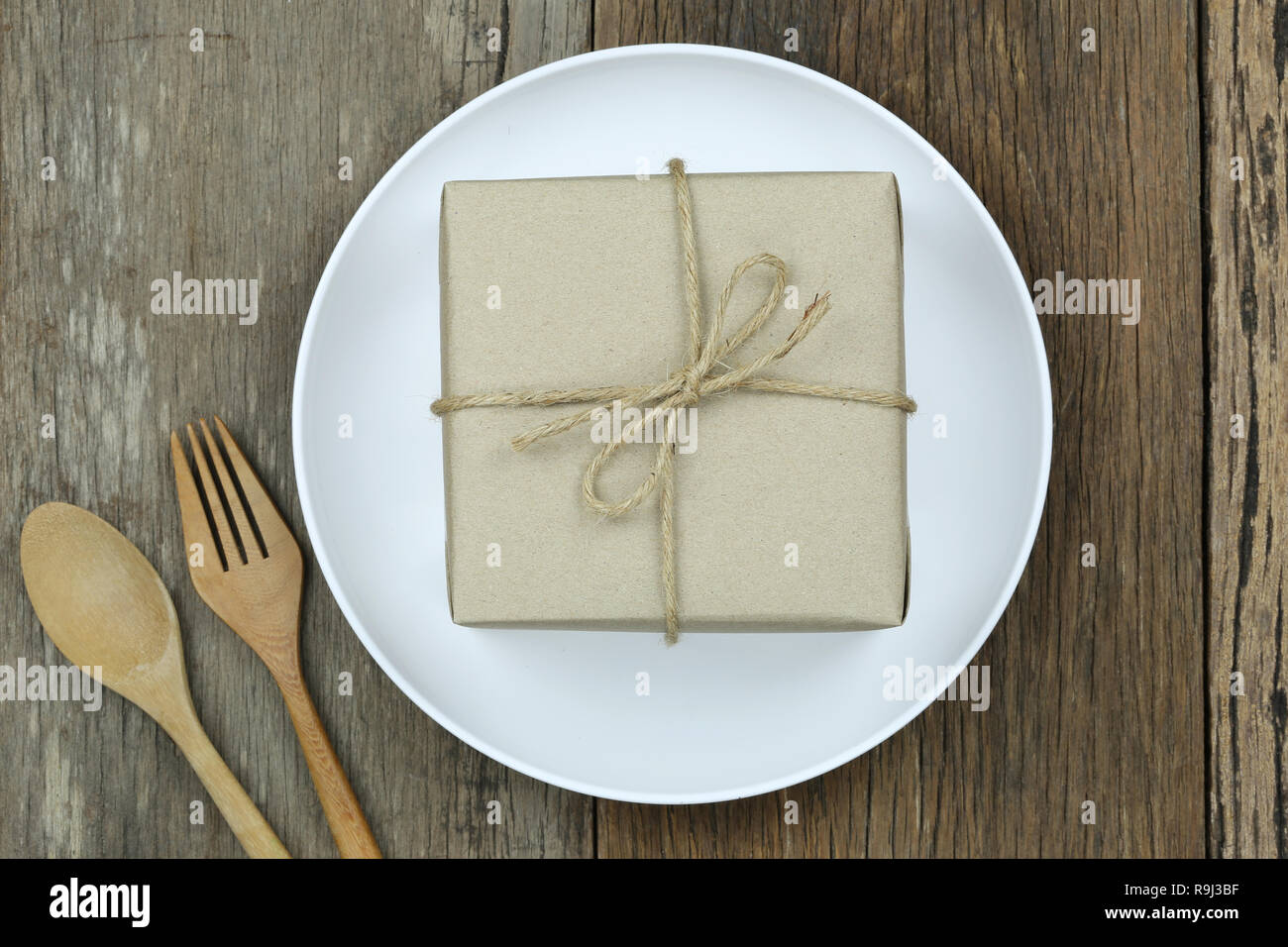 Brown boîte-cadeau en blanc plat sur un sol en parquet et d'avoir une cuillère en bois pour Noël concept. Banque D'Images