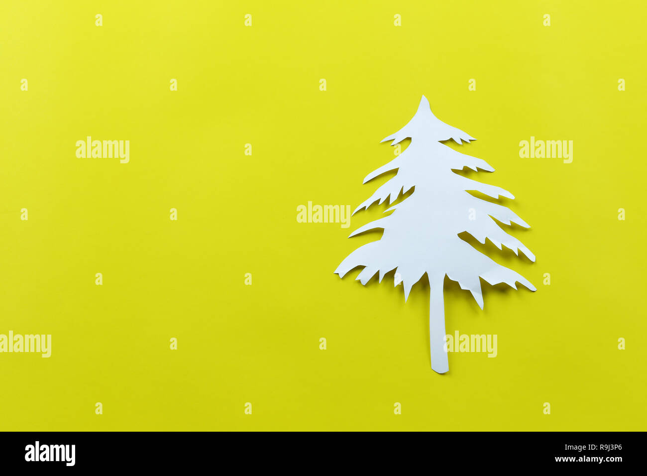 La forme de l'arbre de Noël de papier blanc sur du papier jaune arrière-plan de conception dans votre festival concept. Banque D'Images
