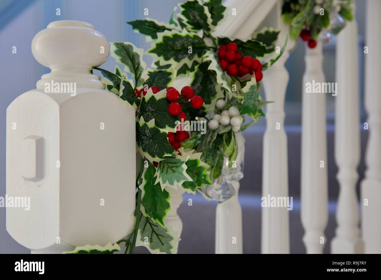 Le gui et houx guirlande de noël enlacés autour d'une magnifique escalier blanc Banque D'Images