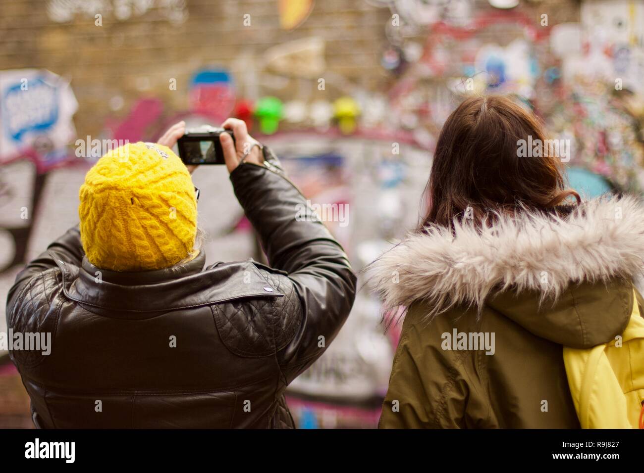 Deux femmes prenant une photo d'un mur de graffitis dans Brick Lane, East London Banque D'Images
